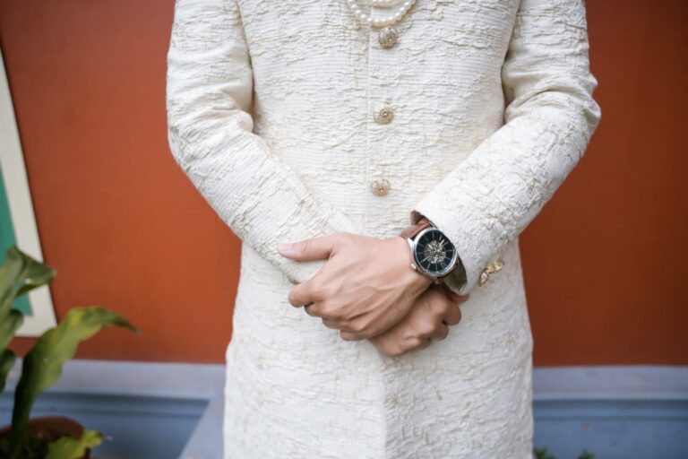 Close-up of a groom wearing a cream sherwani and wristwatch, captured by Aceoclock wedding photography company in Kerala.