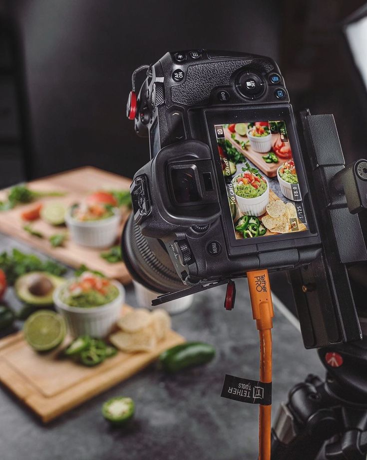 Behind-the-scenes food photography setup with a professional camera capturing a styled dish in a studio, showcasing commercial food photography production
